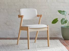 Close up photo of Bella hardwood dining chair in natural with beige fabric in a modern dining room