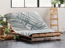 palm reversible outdoor rug on palettes with plants