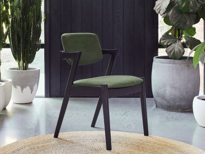 Side view photo of Bella black hardwood dining chair with green fabric in a modern dining room