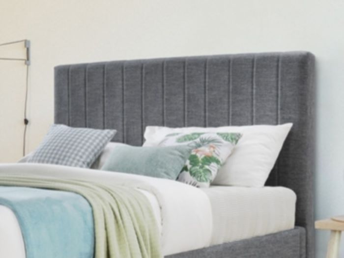 Close up photo of modern bedroom containing cannes queen upholstered headboard in charcoal fabric