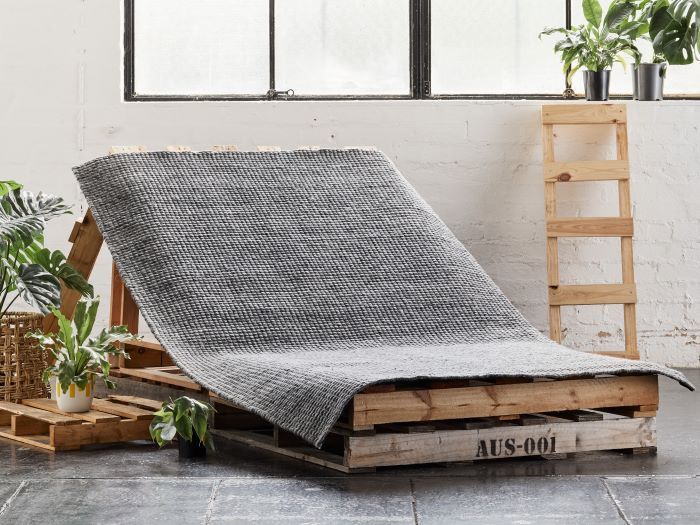 giza indoor wool area rug in charcoal on palettes with plants