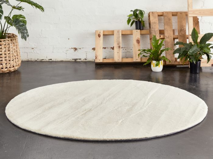 jenna fluffy round cream rug on floor with palettes and plants