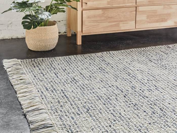 close up photo of blue jocasta hand loomed wool rug on floor with modern furniture